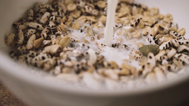 牛奶被倒进一碗麦片粥和早餐燕麦粥的慢镜头视频素材