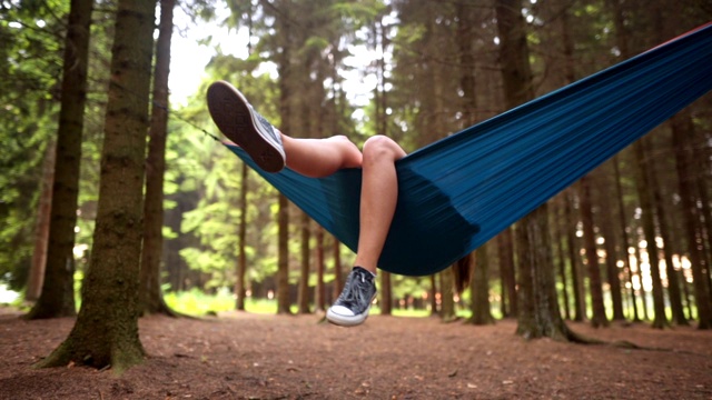 无忧无虑的女孩躺在一张吊床上，享受着森林里的一天视频下载