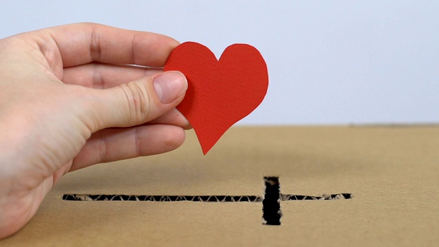 志愿者将纸心脏放入有十字孔的盒子中，捐献心脏视频下载