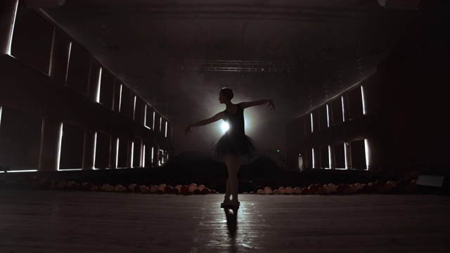 优雅的芭蕾舞者穿着黑色芭蕾舞裙在工作室与烟雾。和背光。视频素材