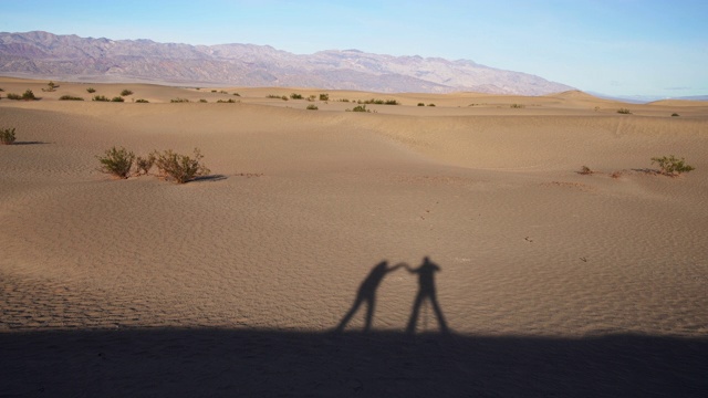 舞蹈的阴影。两个朋友没有出现在视频中，只有他们的影子在沙丘上跳舞，死亡谷，加利福尼亚。视频下载