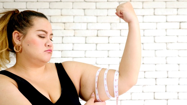 一个不幸的超重妇女用测量尺测量手臂的特写视频下载