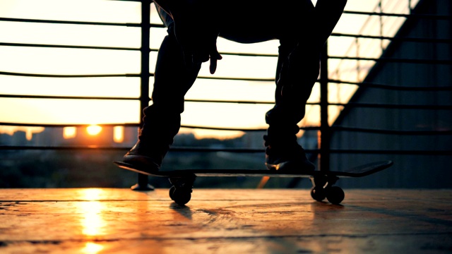 缓慢的运动。剪影滑板滑板和跳跃在夕阳的背景。视频素材