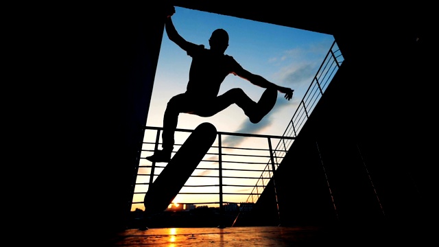 一名滑冰运动员在夕阳下跳跃，慢动作。视频素材