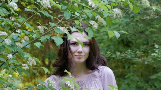一个黑发长发的女孩的肖像，在树林中漫步，触摸着树枝和树叶。视频素材