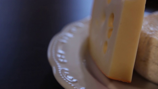 桌上摆着一盘埃芒塔尔奶酪和阿迪盖奶酪。摄像机在它周围移动。close-up.macro。视频下载