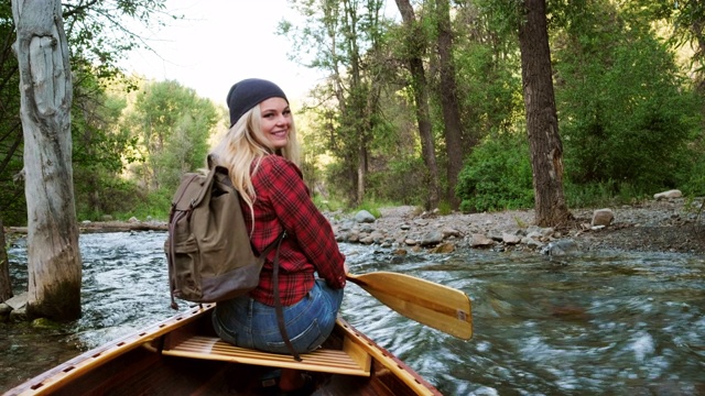 年轻的成年女子在荒野河上的独木舟上视频素材