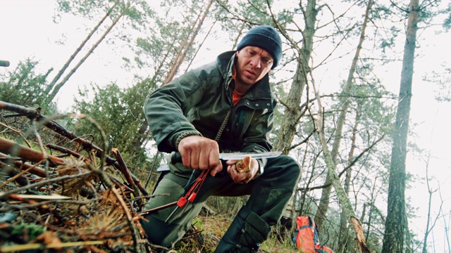 一名男子用他的刀在自然界中磨树枝视频下载