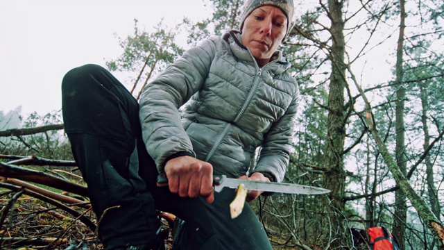 一个女人用她的刀在大自然中磨树枝视频下载