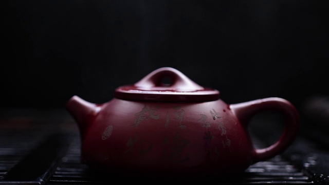 热气腾腾的泥茶壶。用象形文字浇红棕色茶壶。视频下载
