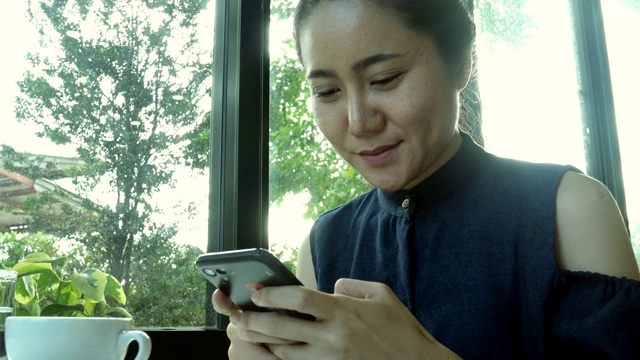 年轻女子在智能手机咖啡馆聊天和发短信。视频素材