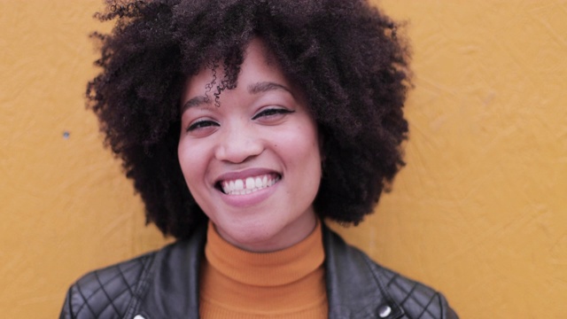 非裔美国年轻人的肖像靠在亮黄色的墙上笑视频下载