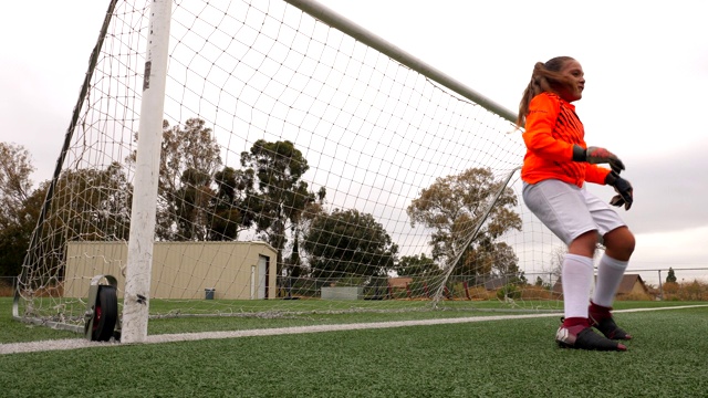 年轻的女足球守门员在练习中跳水射门视频下载