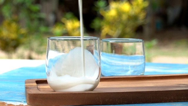 一瓶牛奶和一杯牛奶放在蓝色的木桌上，健康的乳品理念视频素材