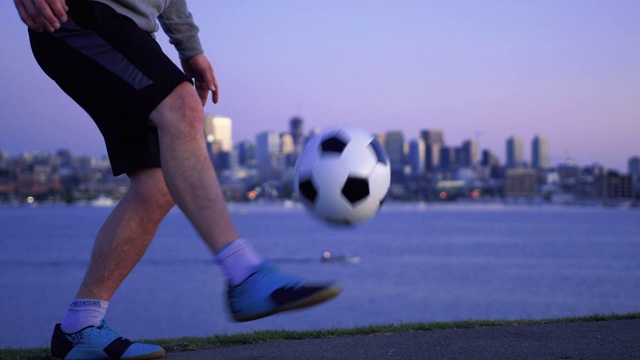 傍晚滨水城市景观与慢动作足球杂耍视频下载