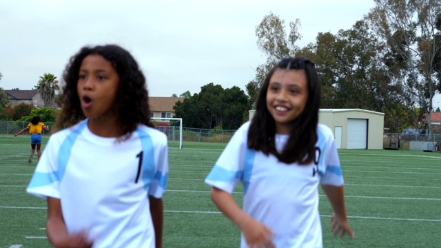 比赛结束后，微笑的年轻女足球运动员和受伤的队友一起穿过场地视频素材