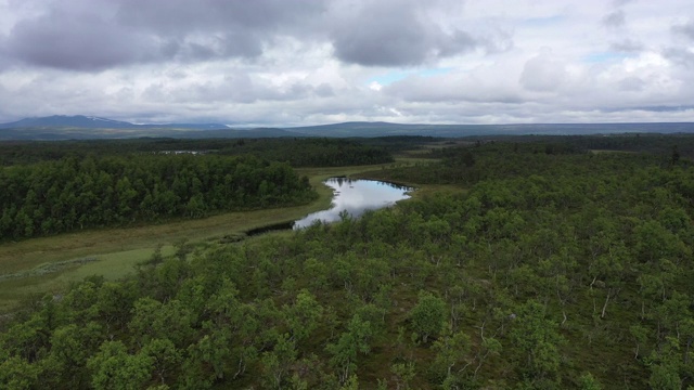 无人机视频飞向一个被绿色森林包围的山湖视频下载