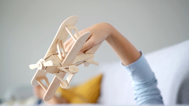 男孩的手玩木制飞机玩具模型的慢镜头。老式运输玩具概念视频。视频素材