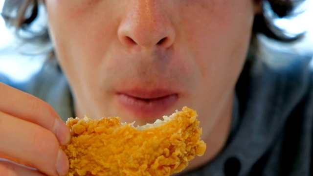 穿灰色连帽衫的人吃黄色的辣味快餐鸡肉视频素材