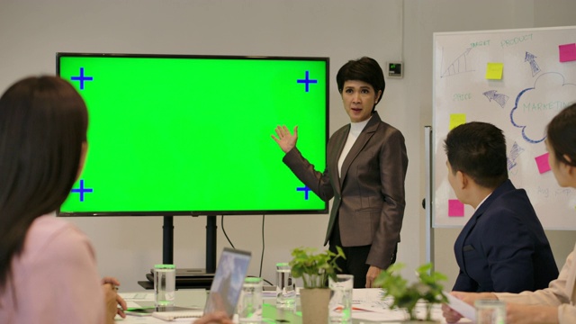 业务演示。迷人的女商人在绿色屏幕前向她在会议室的同事做报告。视频素材