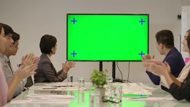 创意业务团队看着会议室的绿色屏幕为发言人鼓掌。视频素材