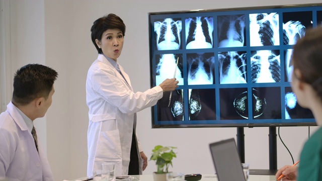 4K亚洲医生团队在会议室开会，他们正在讨论病人的x光结果并寻找诊断。视频下载