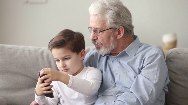 老爷爷和小孙子在用智能手机看手机视频素材