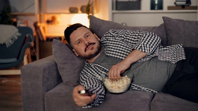 有魅力的男人晚上在舒适的家里看电视电影的肖像视频素材