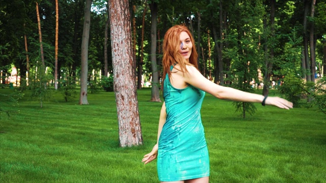 红头发的年轻女子穿着湿衣服和胡里节油漆笑和跳跃在公园视频素材