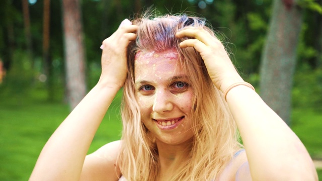 近距离的肖像，愉快的金发女孩与彩色粉在脸上和头发视频素材
