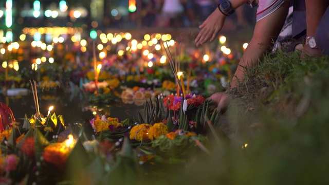 人们把一根烧着的蜡烛放在满是漂浮的水蛇的水中。庆祝一个传统的泰国节日- Loy Krathong视频下载
