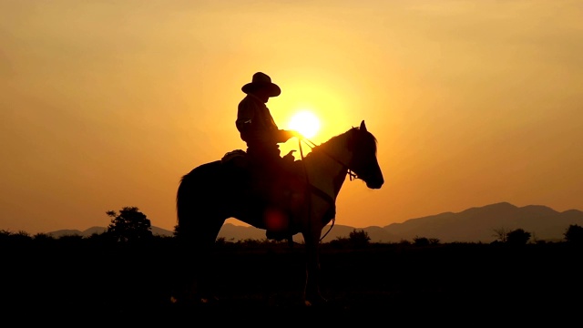 慢动作拍摄的牛仔骑马和拿着枪在日落视频下载