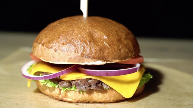 美味的汉堡配上牛肉片，生菜，番茄，洋葱，棕色的纸。视频素材