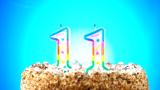 生日蛋糕和燃烧的生日蜡烛。11号。背景的颜色变化视频下载
