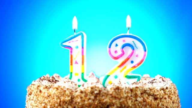 生日蛋糕和燃烧的生日蜡烛。12号。背景的颜色变化视频下载