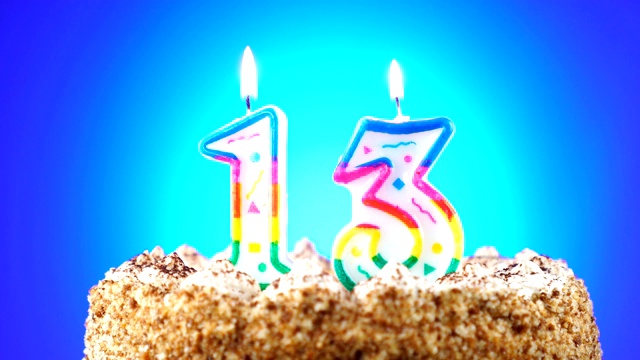 生日蛋糕和燃烧的生日蜡烛。13号。背景的颜色变化视频下载