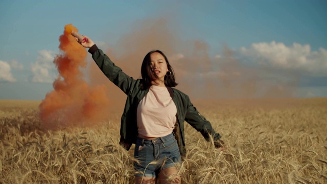 兴奋的亚洲女孩与烟雾弹在野外日落视频素材