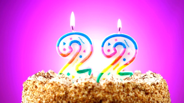 生日蛋糕和燃烧的生日蜡烛。22。背景的颜色变化视频下载