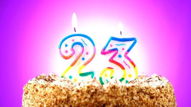 生日蛋糕和燃烧的生日蜡烛。23号。背景的颜色变化视频下载