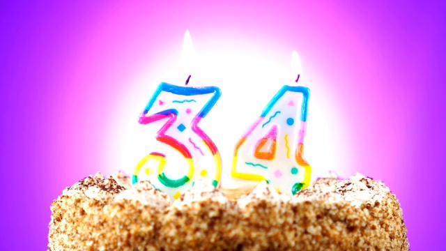 生日蛋糕和燃烧的生日蜡烛。34号。背景的颜色变化视频下载