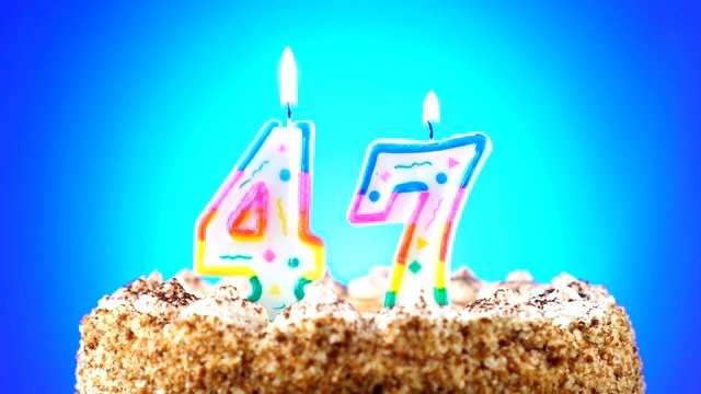 生日蛋糕和燃烧的生日蜡烛。47号。背景的颜色变化视频素材