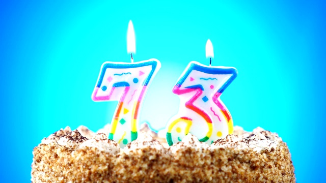 生日蛋糕和燃烧的生日蜡烛。73号。背景的颜色变化视频素材