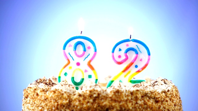 生日蛋糕和燃烧的生日蜡烛。82号。背景的颜色变化视频素材
