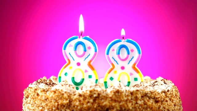 生日蛋糕和燃烧的生日蜡烛。88号。背景的颜色变化视频素材