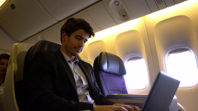 年轻的商人乘飞机去参加商务会议，在笔记本电脑上工作视频素材