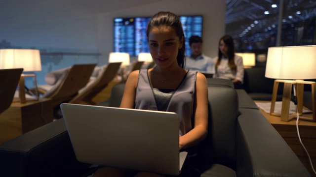 美丽的女商人在机场贵宾休息室用笔记本电脑工作视频素材
