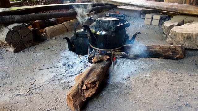 用灰烬烧开水壶，用木柴生火，这就是露营的概念视频素材