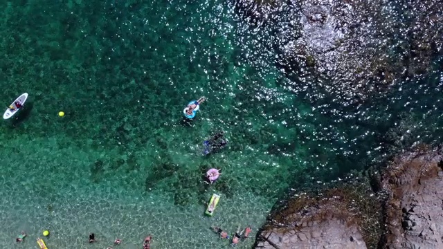 无人机自拍，快乐的女人穿着漂浮在海上的充气甜甜圈。视频下载
