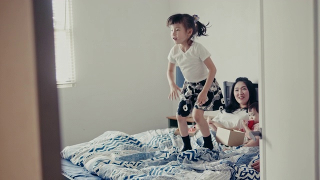 年轻的台湾女孩在母亲节快乐地在床上跳(慢镜头)视频素材