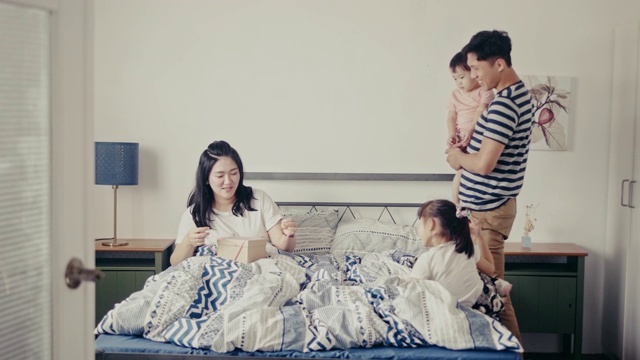 年轻的中国女儿在卧室里给妈妈一个礼物(慢镜头)视频素材